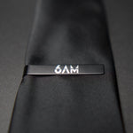 6AM Tie Clip handmade black stainless steel with 6AM logo engraved on a black tie close-up view