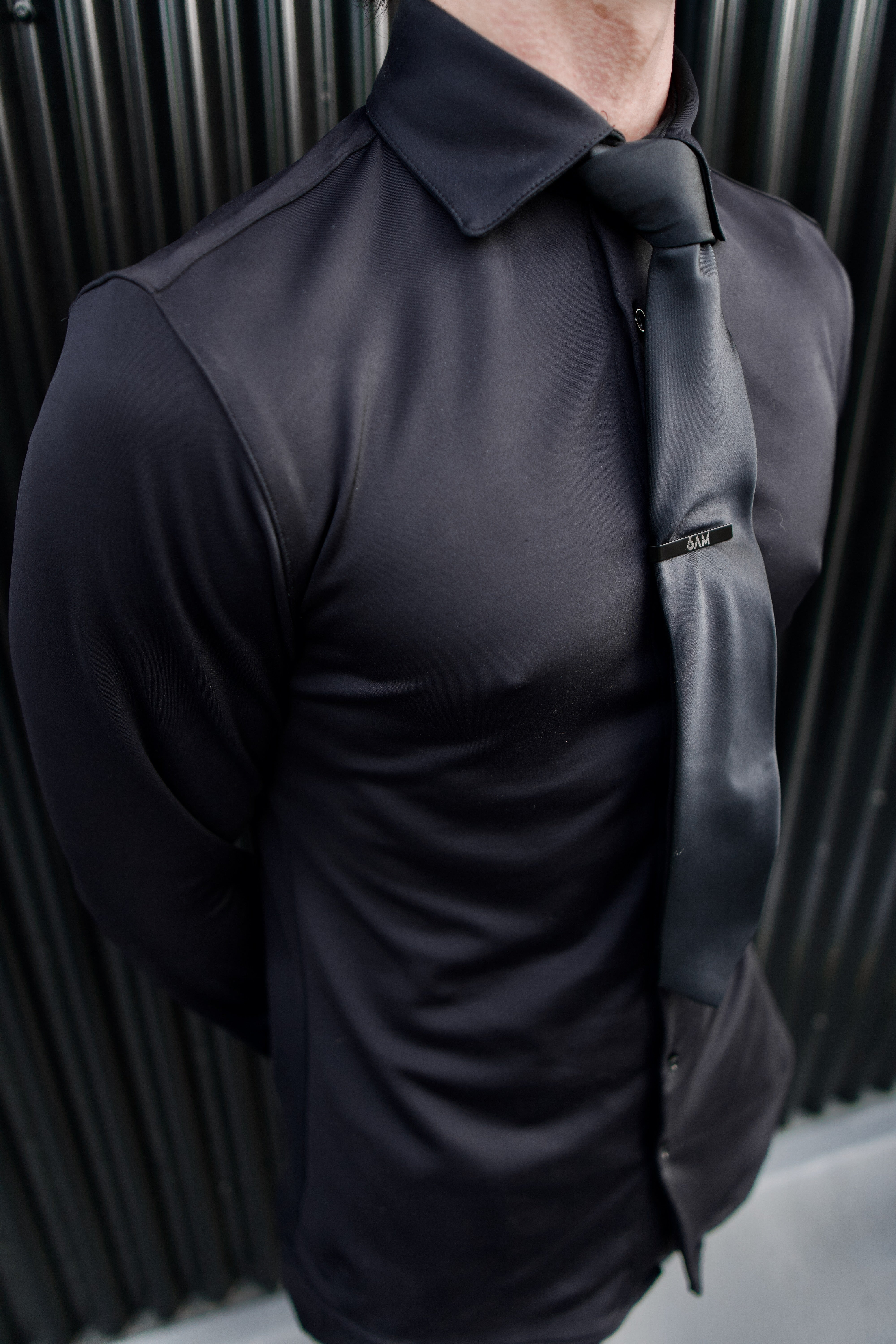 Man wearing a black Never-Iron Work Shirt with a black tie, showcasing its smooth, wrinkle-free fabric and fit.