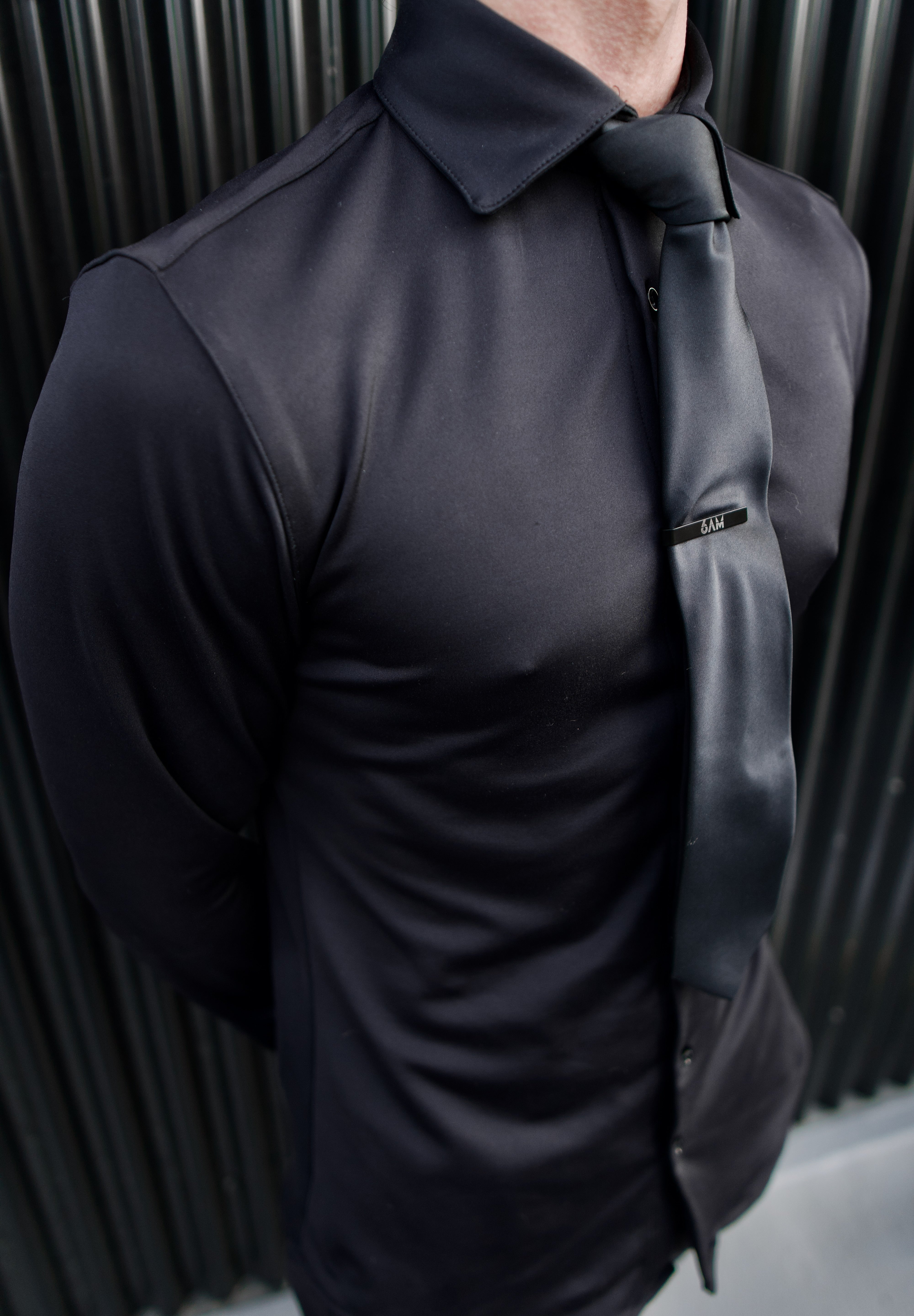 Man wearing a black Never-Iron Work Shirt with a black tie, showcasing its smooth, wrinkle-free fabric and fit.