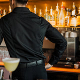 Men's Work Shirt slim fit sweat-proof design worn by bartender behind bar with drinks and bottles.