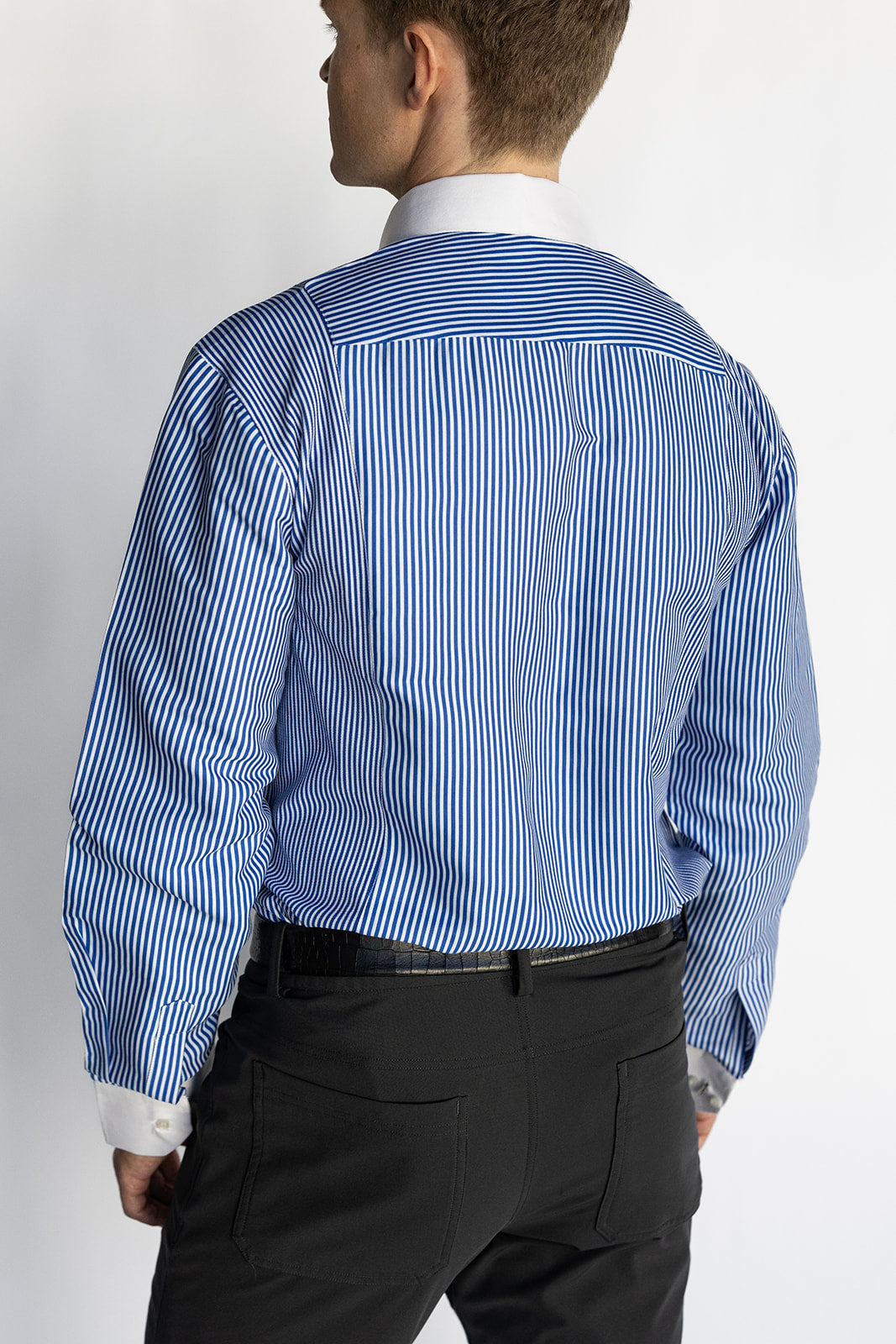 Person wearing a blue striped shirt and black pants on a white background