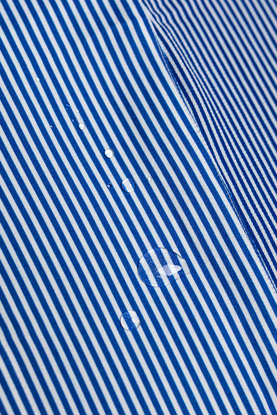 Close-up of blue and white striped fabric with visible texture and water droplet