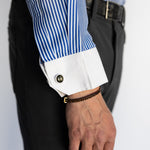 Close-up of a person wearing a blue and white striped shirt with rolled-up sleeves and black pants.