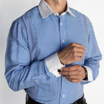 Man wearing a blue and white striped dress shirt with rolled-up sleeves on a plain background