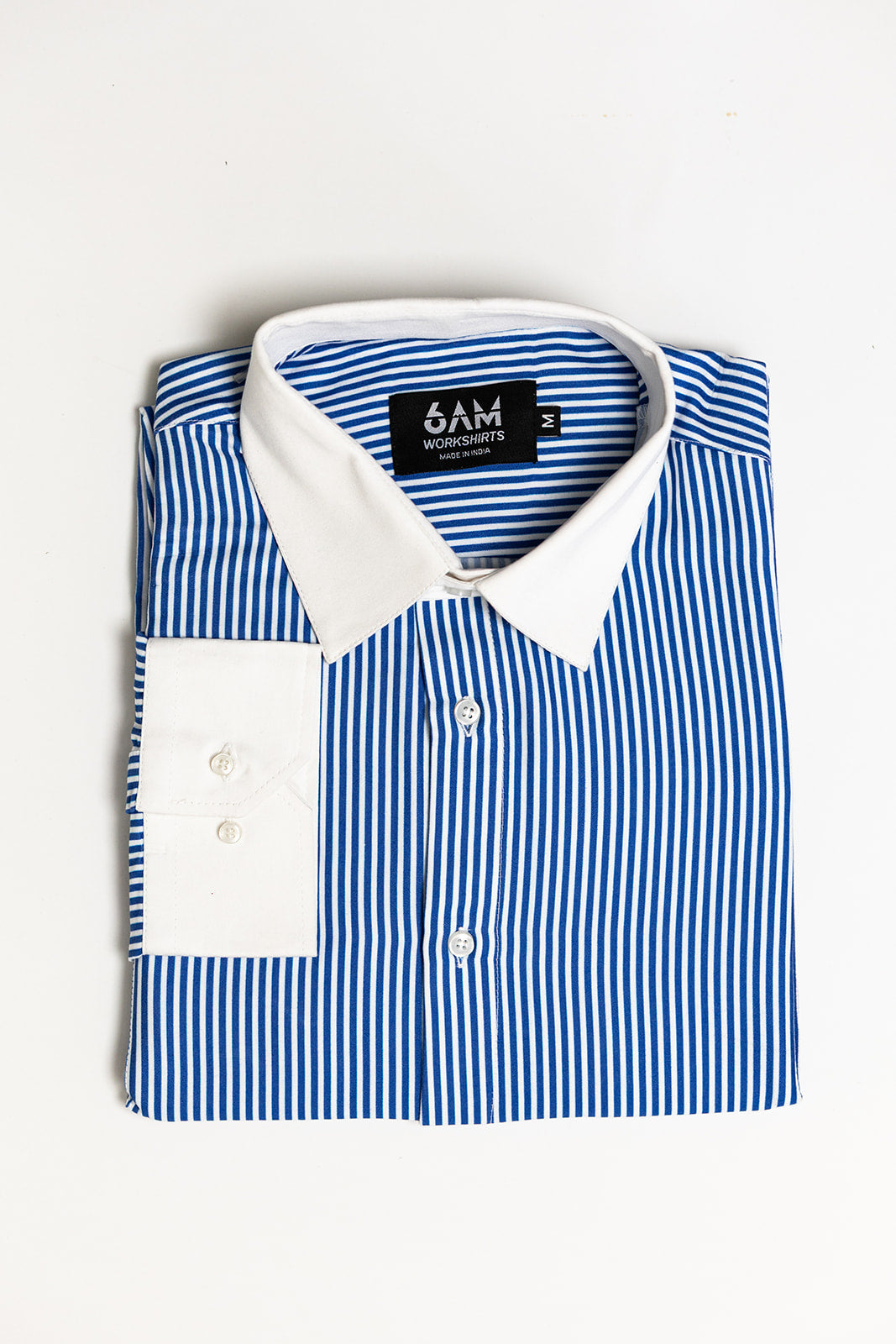Folded blue and white striped shirt with a visible brand label on a light gray background