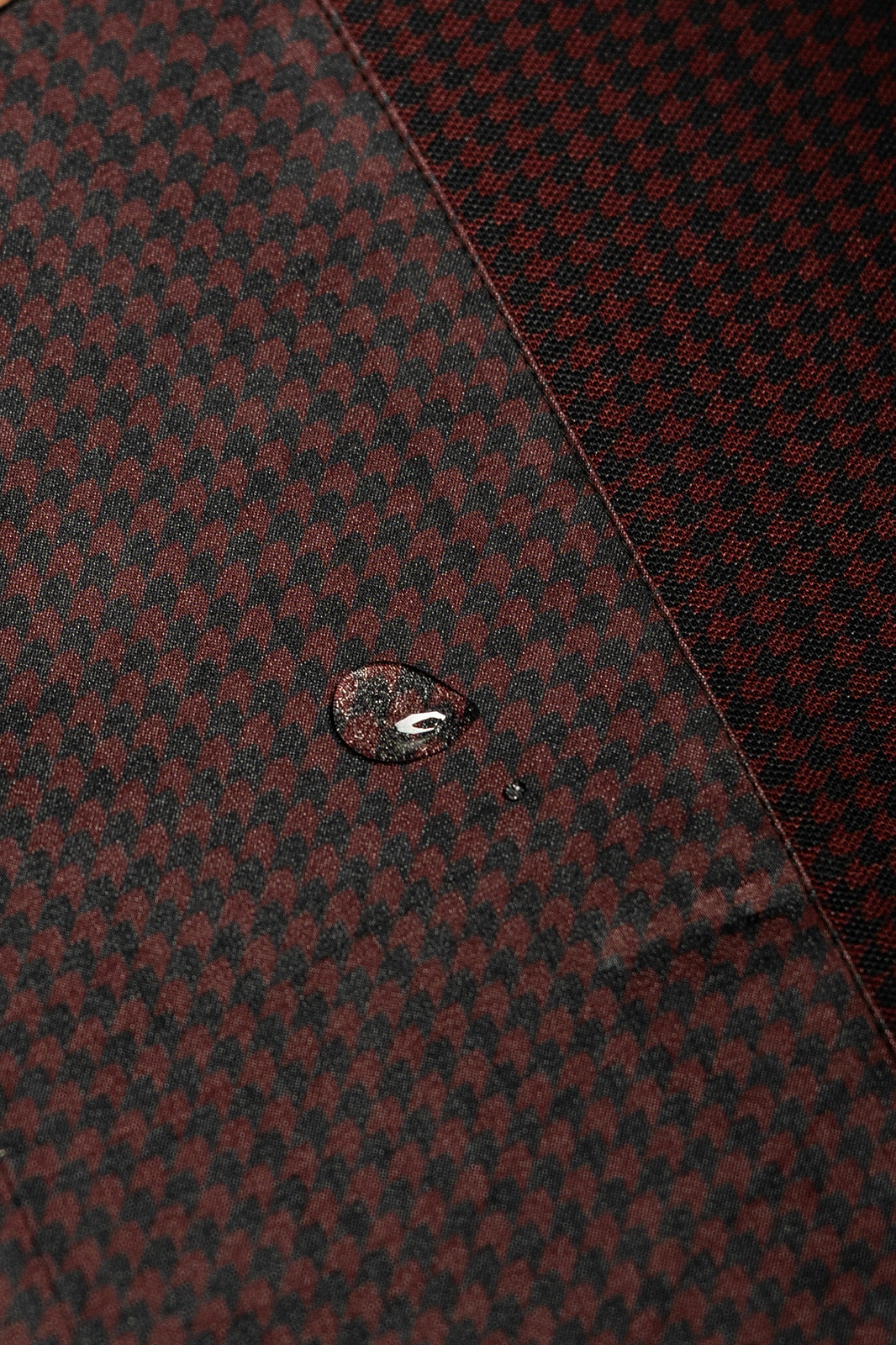Close-up of water beading on the burgundy and black Bordeaux Arrowhead WorkShirt performance fabric.