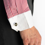 Close-up of a red and white striped shirt cuff with a button, worn with a dark suit.