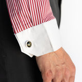 Close-up of a red and white striped shirt cuff with a button, worn with a dark suit.