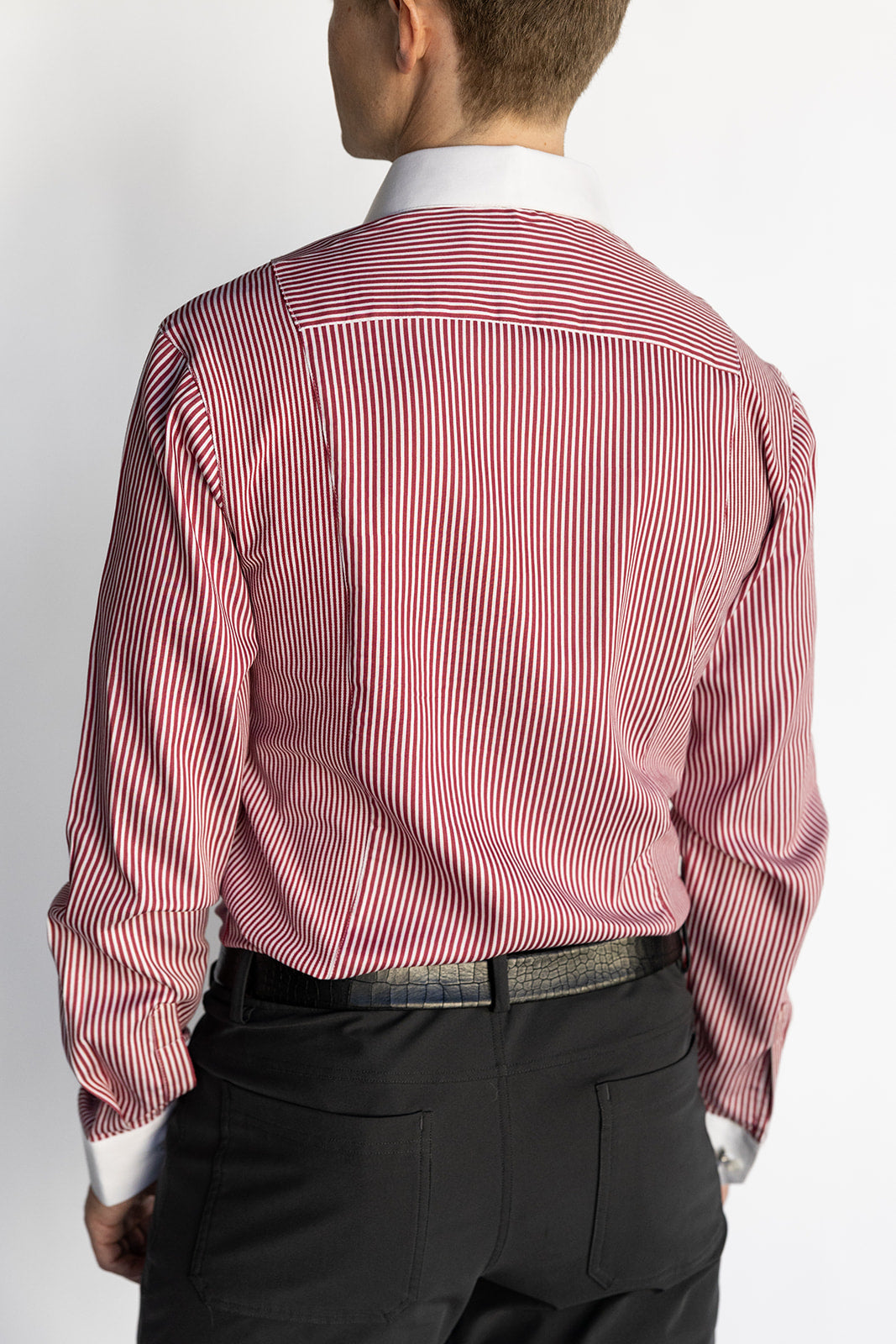 Man wearing a red and white striped dress shirt with black pants on a white background