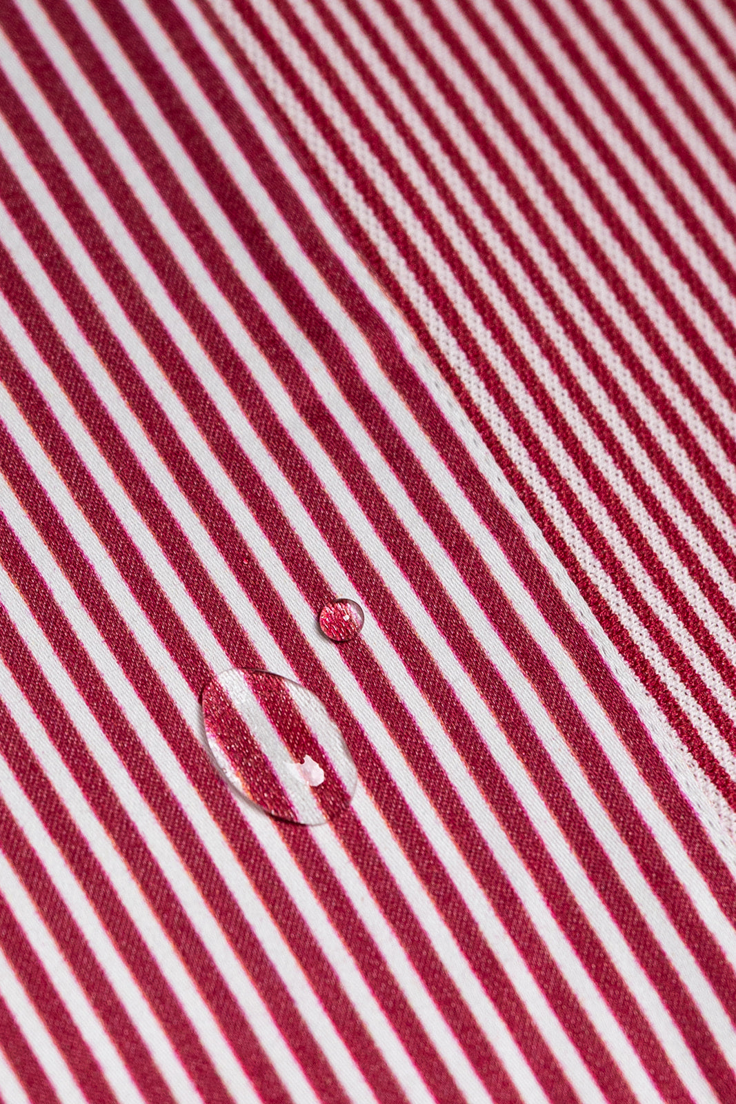 Close-up of red and white striped fabric with a water droplet.