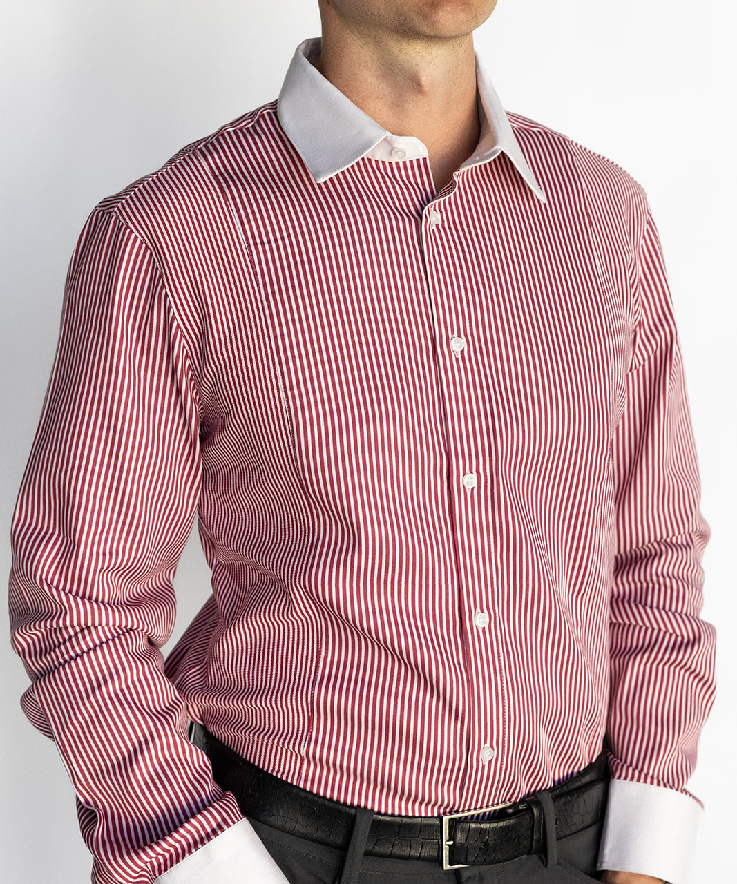 Man wearing a red and white striped dress shirt with a plain background