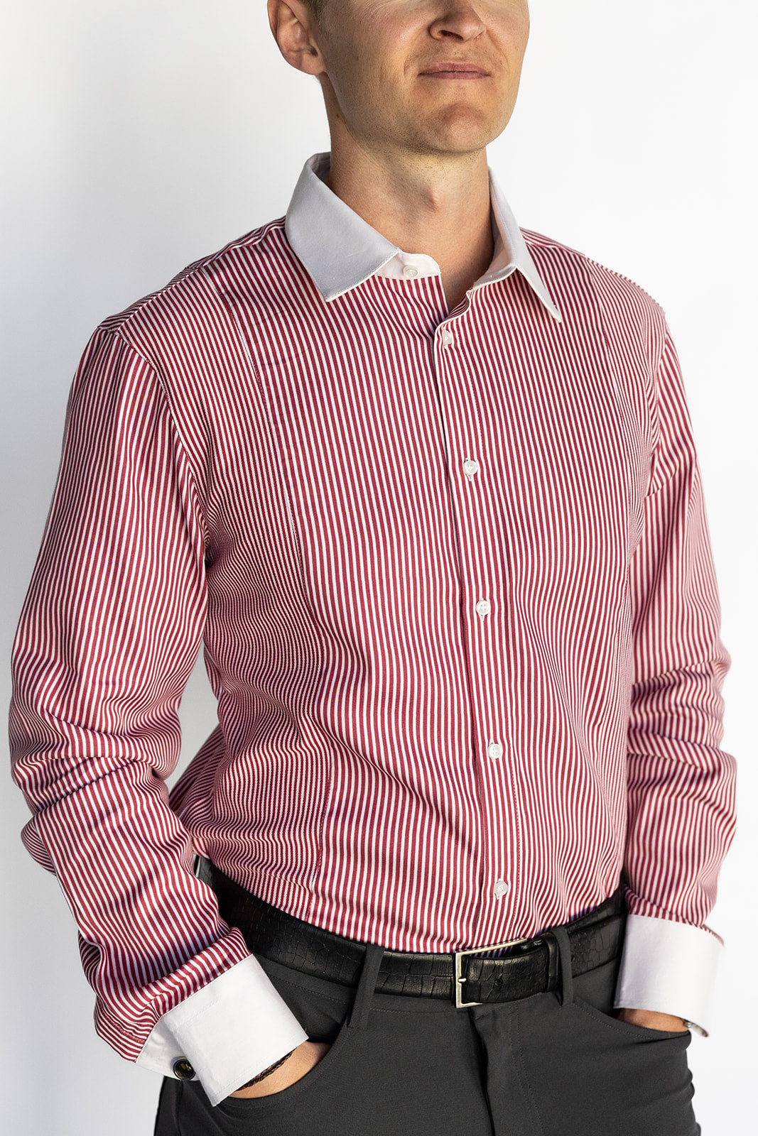 Man wearing a red and white striped dress shirt with a plain background
