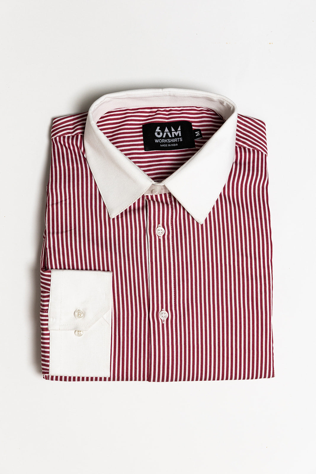 Folded red and white striped shirt with a visible brand label on a light gray background