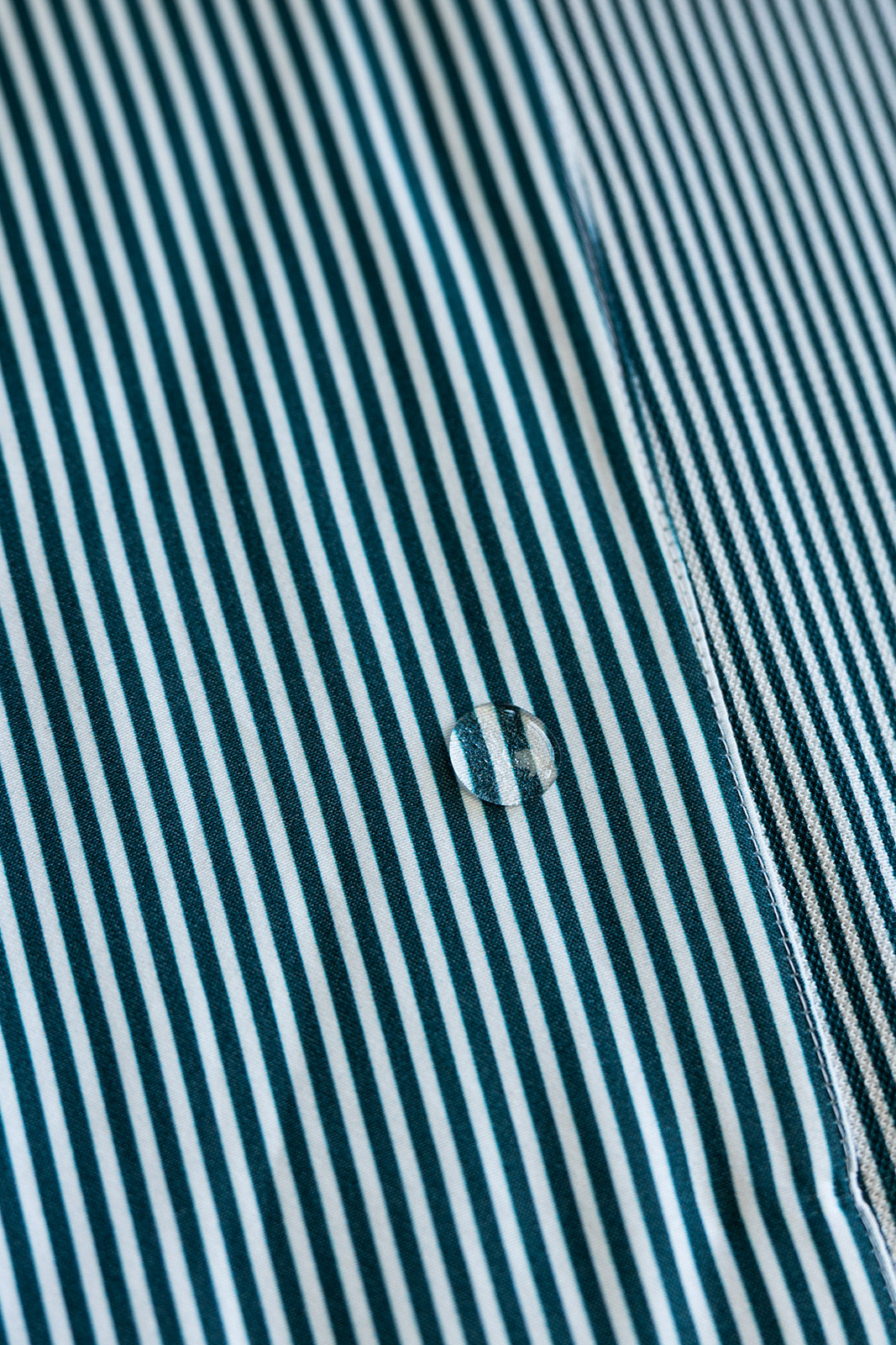 Close-up of a water droplet on a green and white striped fabric surface