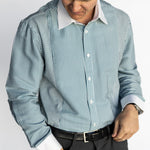 Man wearing a striped shirt and dark pants on a light gray background