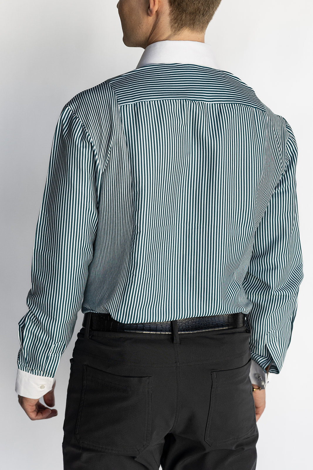 Man wearing a striped dress shirt and black pants on a plain background