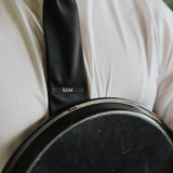 6AM Tie Clip black stainless steel engraved logo on black tie worn with white shirt and jacket