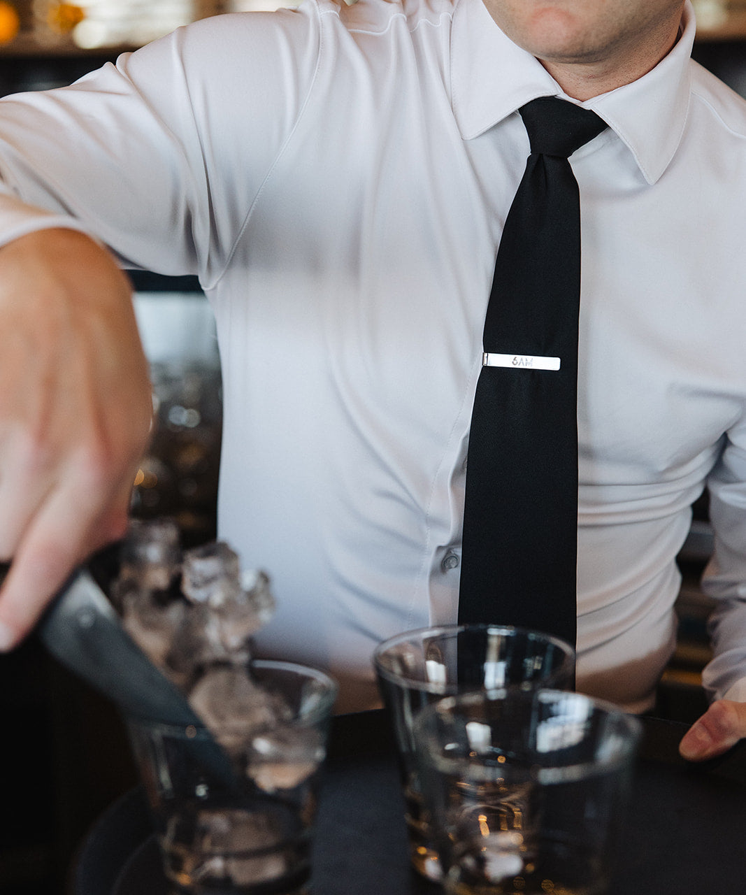 Man wearing a white Never-Iron Work Shirt with black tie serving drinks, showcasing wrinkle-free fabric and fit.