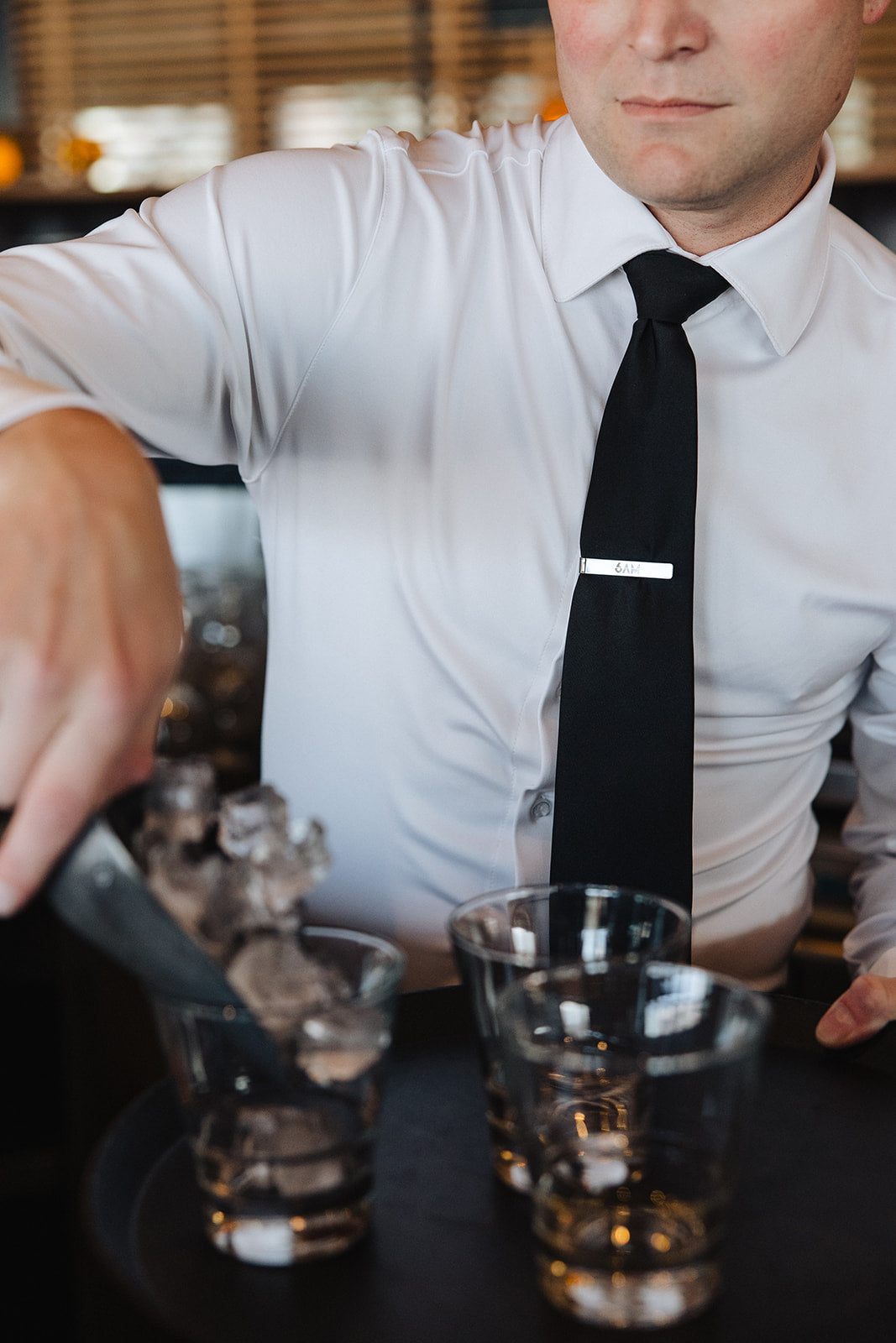Man wearing a white Never-Iron Work Shirt with black tie serving drinks, showcasing wrinkle-free fabric and fit.