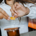 Woman wearing white Women's Work Shirt with form-fitting design preparing a drink in a bar setting.
