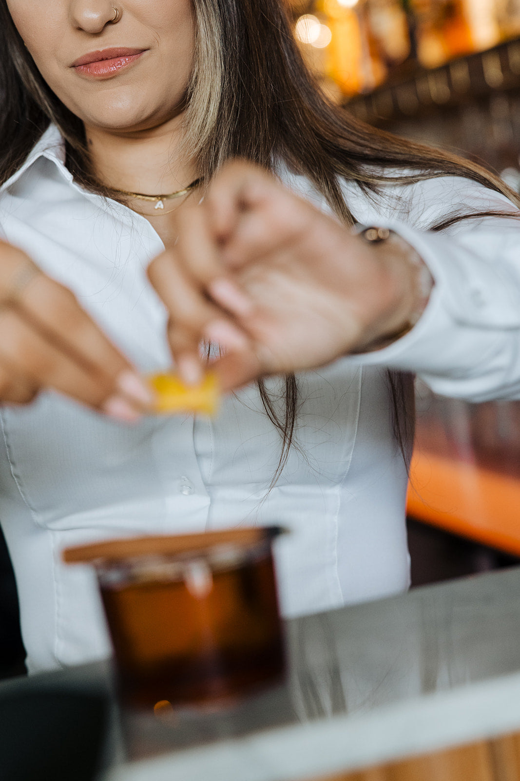Woman wearing white Women's Work Shirt with form-fitting design preparing a drink in a bar setting.