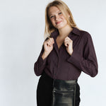 Woman wearing the Women’s Long Sleeve Bordeaux Arrowhead WorkShirt in a deep burgundy and black geometric pattern against a light background.