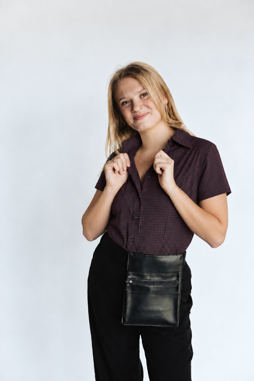 Woman wearing the Women’s short-sleeve Bordeaux Arrowhead WorkShirt in burgundy and black against a light studio background.