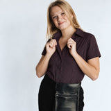 Woman wearing the Women’s short-sleeve Bordeaux Arrowhead WorkShirt in burgundy and black against a light studio background.