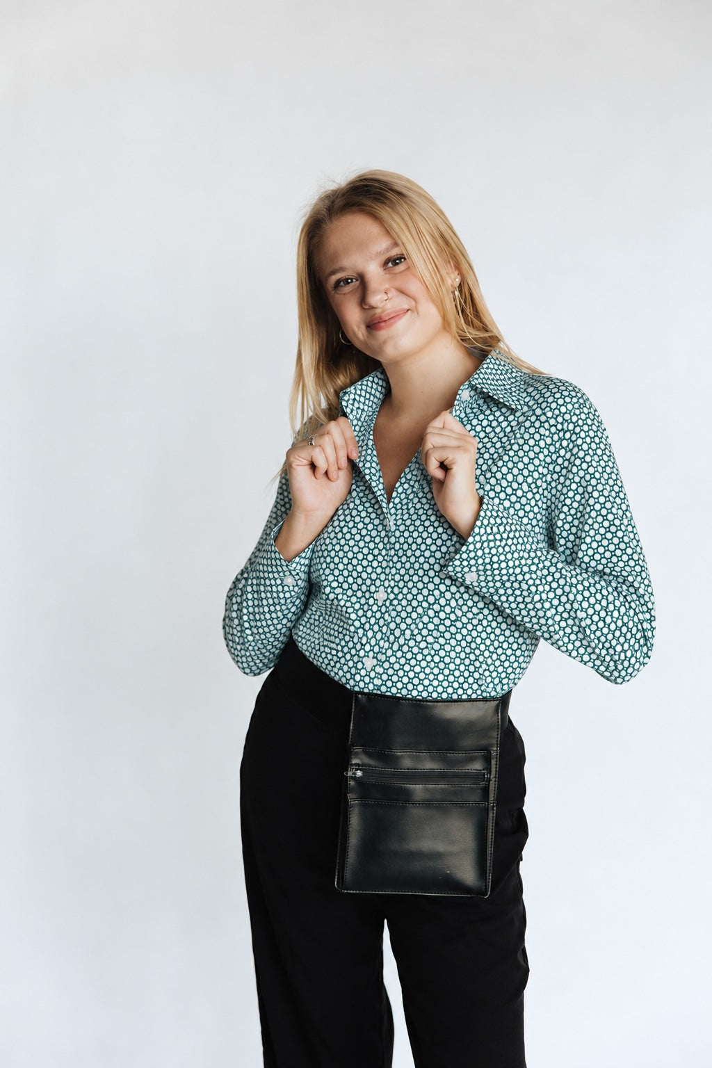 Woman wearing a emerald green hexagon-pattern WorkShirt with black pants and a server pouch