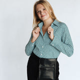 Woman wearing a emerald green hexagon-pattern WorkShirt with black pants and a server pouch