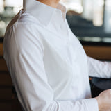 Profile view of a woman wearing a white Women's Work Shirt with a crisp collar and fitted design.