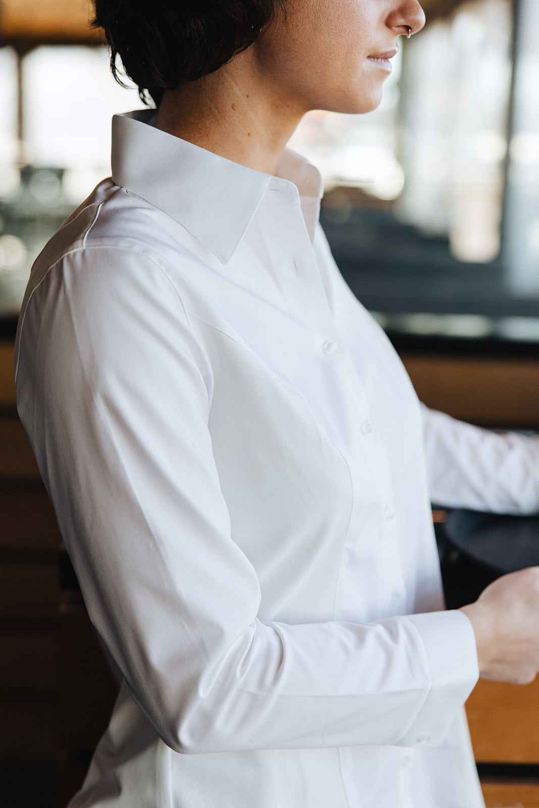 Profile view of a woman wearing a white Women's Work Shirt with a crisp collar and fitted design.