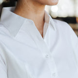 Close-up of woman wearing a stylish, breathable, and sweat-proof Women's Work Shirt by 6AM in white.