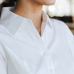 Close-up of woman wearing a stylish, breathable, and sweat-proof Women's Work Shirt by 6AM in white.