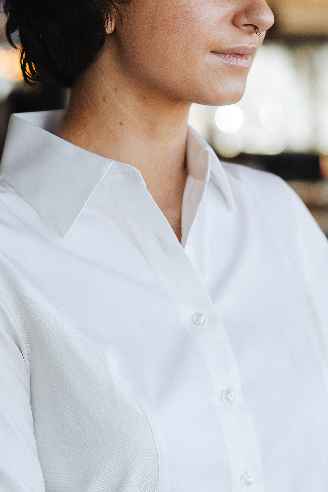 Close-up of woman wearing a stylish, breathable, and sweat-proof Women's Work Shirt by 6AM in white.